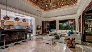A spacious living area with a modern kitchen, a bar area, and a comfortable seating arrangement. - The Residence Seminyak (Seminyak)