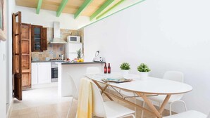 Una cocina moderna con armarios blancos, un microondas y un comedor con una mesa redonda y sillas blancas.