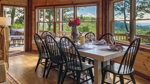 A wooden dining area with a table set for six, surrounded by large windows offering a view of the outdoors. - Experience North GA Mtn Retreat: Views w/ Hot Tub (Morganton)