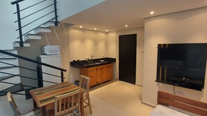 A modern interior with a staircase, a kitchen area, and a dining space. - Duplex apartment in Villa Licuri (são sebastião)