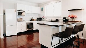 Una cocina moderna con armarios blancos, una isla central con taburetes y un horno empotrado.