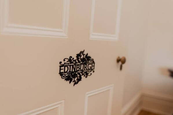 Una puerta con un letrero decorativo que dice "EDINBURGH" en una tipografía estilizada.