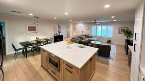 Eine geräumige Küche mit einer zentralen Kochinsel, Holzschränken und einem Essbereich mit Tisch und Stühlen.