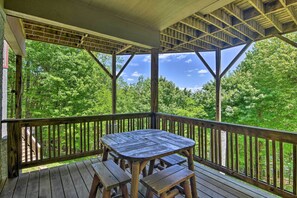 A wooden deck with a table and benches, surrounded by a wooden railing, overlooking a forested area. - Contemporary Cabin on the Peak of Seven Devils (Seven Devils)