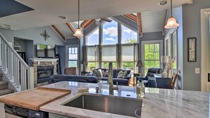 A spacious kitchen with a large island, a dining area with a blue sofa, and a view of the outdoors through large windows.
