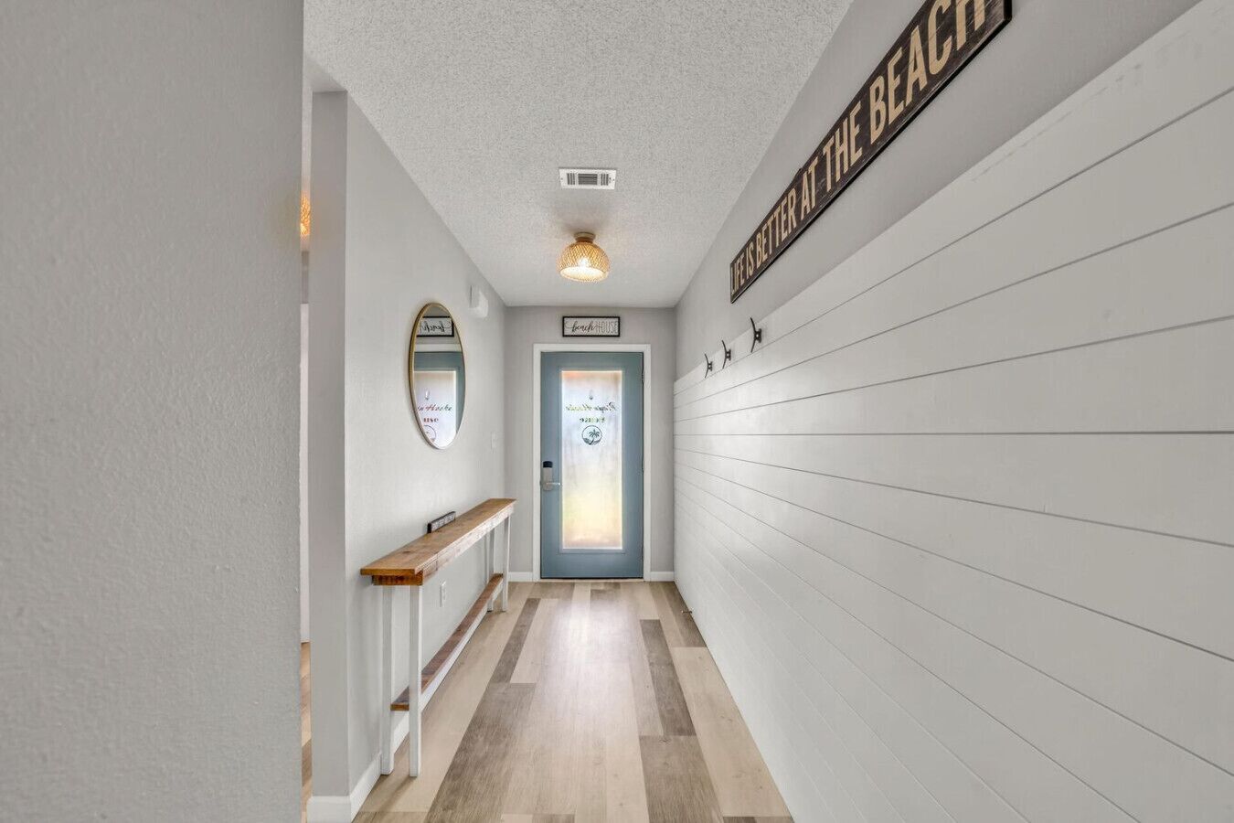 A hallway with a wooden bench, a mirror, and a door labeled "Beach House".