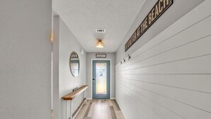 A hallway with a wooden bench, a mirror, and a door labeled "Beach House".