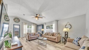 A spacious living room with two sofas, a coffee table, and a ceiling fan.