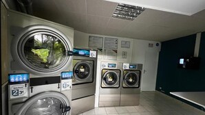 Eine Waschsalon mit mehreren Waschmaschinen, einer digitalen Anzeige und einem gefliesten Boden.