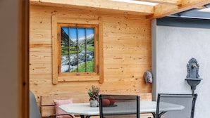 Un intérieur en bois avec une table et des chaises, une fenêtre donnant sur la montagne et un luminaire fixé au mur.