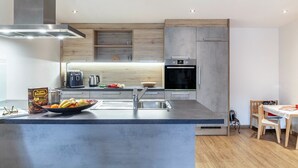 Une cuisine moderne dotée d’un îlot central, d’appareils électroménagers intégrés et d’un coin repas avec une table et des chaises.
