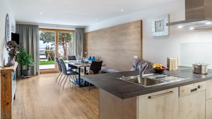 Une cuisine moderne dotée d’un îlot central, d’un coin repas avec des chaises et d’une grande fenêtre.