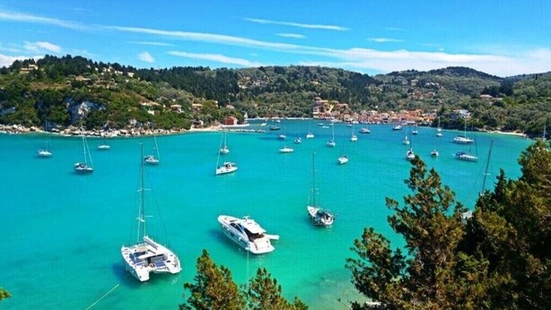 A coastal marina with numerous sailboats docked, surrounded by hills and a small town. - Holiday Home 'Ria Sweet Home Paxos' with Private Terrace, Private Garden and Wi-Fi (Corfu)