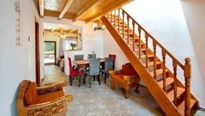 A dining area with a wooden staircase, a dining table with chairs, and a view into another room. - Holiday Home 'Ria Sweet Home Paxos' with Private Terrace, Private Garden and Wi-Fi (Corfu)