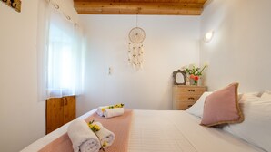 A bedroom with a bed, a bedside table with a mirror, a dresser, and a dreamcatcher on the wall. - Holiday Home 'Ria Sweet Home Paxos' with Private Terrace, Private Garden and Wi-Fi (Corfu)