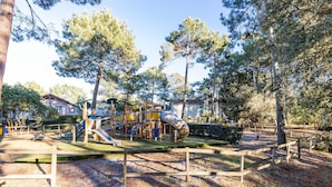 A playground with a slide, climbing structures, and a fenced area. - House with View, Shared Pool and Garden (Lacanau-Ocean)