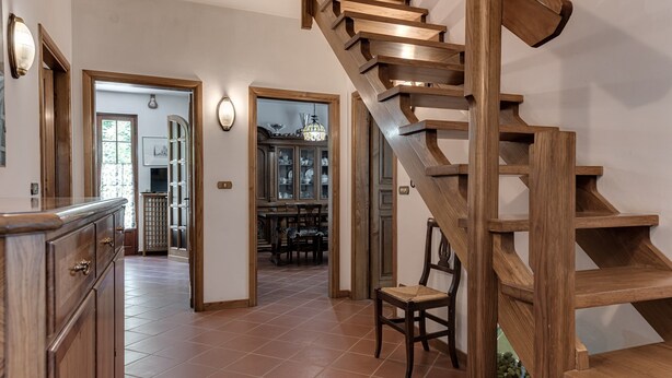 A wooden staircase leading to an upper floor, a kitchen area with cabinets and a dining table, and a hallway with a view into a dining room. - Holiday Home 'Gigli Di Firenze' with Mountain View, Wi-Fi and Air Conditioning (Rufina)