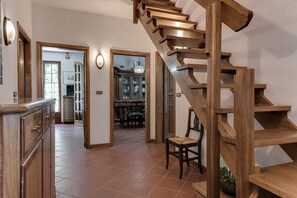 A wooden staircase leading to an upper floor, a kitchen area with cabinets and a dining table, and a hallway with a view into a dining room. - Holiday Home 'Gigli Di Firenze' with Mountain View, Wi-Fi and Air Conditioning (Rufina)