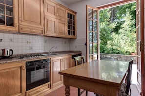 A kitchen with wooden cabinets, a granite countertop, a stove, an oven, and a dining table with chairs. - Holiday Home 'Gigli Di Firenze' with Mountain View, Wi-Fi and Air Conditioning (Rufina)