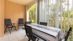 A balcony with a table and chairs, a view of trees, and a building exterior. - Holiday Apartment "Résidence moderne avec piscine" with Shared Pool, Terrace & Wi-Fi (Moliets-et-Maa)