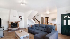 A living room with a sofa, a coffee table, a fireplace, and a staircase. - "Villa Catarina" Vacation Home with Pool & Wi-Fi (Albufeira)