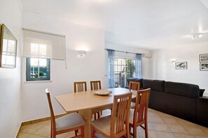Un coin repas avec une table et des chaises, un canapé et une fenêtre avec des rideaux.