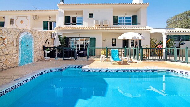 A two-story building with a swimming pool, outdoor seating, and a stone wall with a decorative tile design. - "Villa Catarina" Vacation Home with Pool & Wi-Fi (Albufeira)