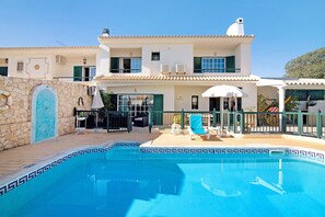 A two-story building with a swimming pool, outdoor seating, and a stone wall with a decorative tile design. - Holiday Home "Villa Catarina" with Pool & Wi-Fi (Albufeira)