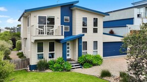Une maison à deux étages avec un balcon, un garage et un jardin bien entretenu.