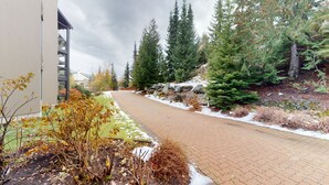 A paved pathway flanked by trees and a building. - Ironwoods Blueberry Hill by Whistler VR (Whistler)
