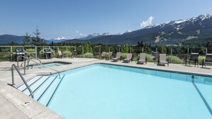 A swimming pool with lounge chairs and a view of snow-capped mountains. - Ironwoods Blueberry Hill by Whistler VR (Whistler)