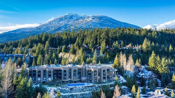 A resort with a central building surrounded by snow-covered trees and a mountain in the background. - Ironwoods Blueberry Hill by Whistler VR (Whistler)