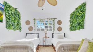Una habitación con dos camas, un ventanal con vistas y decoración de pared verde.