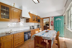 Una cocina con armarios de madera, una mesa de comedor, sillas, un microondas y una cafetera.
