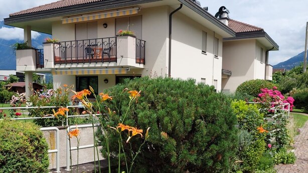 A two-story house with a balcony, surrounded by lush greenery and flowers. - Holiday Apartment "Sweet Dreams" with Mountain View, Balcony and Wi-Fi (Merano)