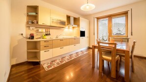 A modern kitchen with wooden cabinets, a built-in oven, and a dining area with a table and chairs. - Holiday Apartment "Sweet Dreams" with Mountain View, Balcony and Wi-Fi (Merano)
