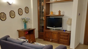 A living room with a sofa, TV, wooden cabinet, and wall-mounted lights. - Holiday Apartment "Sweet Dreams" with Mountain View, Balcony and Wi-Fi (Merano)