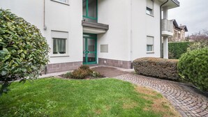 A two-story building with a green door, a small garden, and a paved pathway leading to the entrance. - Holiday Apartment "Sweet Dreams" with Mountain View, Balcony and Wi-Fi (Merano)