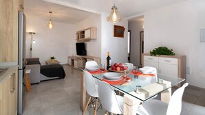 A modern kitchen with a glass dining table, white chairs, and a built-in TV. - Holiday Home "Casa Lía" with Wi-Fi (La Santa)