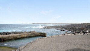 A coastal view with a rocky shoreline, a concrete pier, and a clear sky. - Holiday Home "Casa Lía" with Wi-Fi (La Santa)