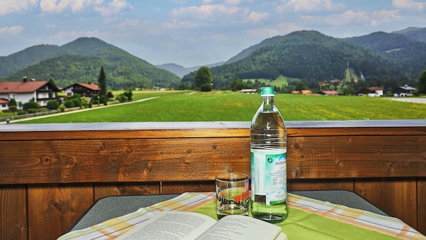 Eine hölzerne Bank mit Tisch, einer Wasserflasche und einem offenen Buch.