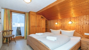 Ein Schlafzimmer mit Holzwänden, einem Bett, Nachttischen und einem Fenster mit Vorhängen.