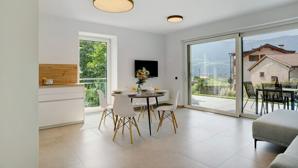 A modern kitchen with a dining area, large sliding glass doors, and a view of the outdoors. - Apartment 'Haus Weinblick Apt 3' with Mountain View, Wi-Fi, and Air Conditioning (Margreid)