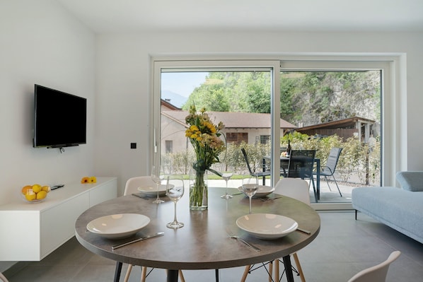 A modern dining area with a round table, white plates, and a vase of flowers.