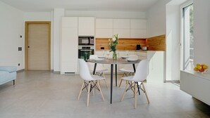 A modern kitchen with white cabinets, a dining table with chairs, and a large window. - Apartment 'Haus Weinblick Apt 3' with Mountain View, Wi-Fi, and Air Conditioning (Margreid)
