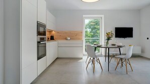 A modern kitchen with white cabinetry, a wooden countertop, and a dining area with a table and chairs. - Apartment 'Haus Weinblick Apt 3' with Mountain View, Wi-Fi, and Air Conditioning (Margreid)