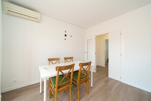 Ein Essbereich mit einem weißen Tisch und Holzstühlen, einer weißen Wand mit einer Nummer und einer Tür, die in einen anderen Raum führt.