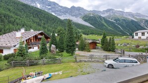 Un village de montagne avec des maisons traditionnelles en bois, une voiture et un mur de pierre.