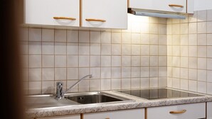 Une cuisine avec des meubles blancs, des poignées en bois, un évier en acier inoxydable et un plan de travail en granit.