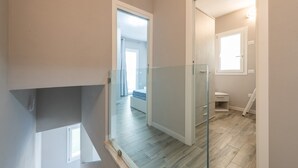 Un interior moderno con un separador de vidrio, piso de madera y vista a otra habitación.